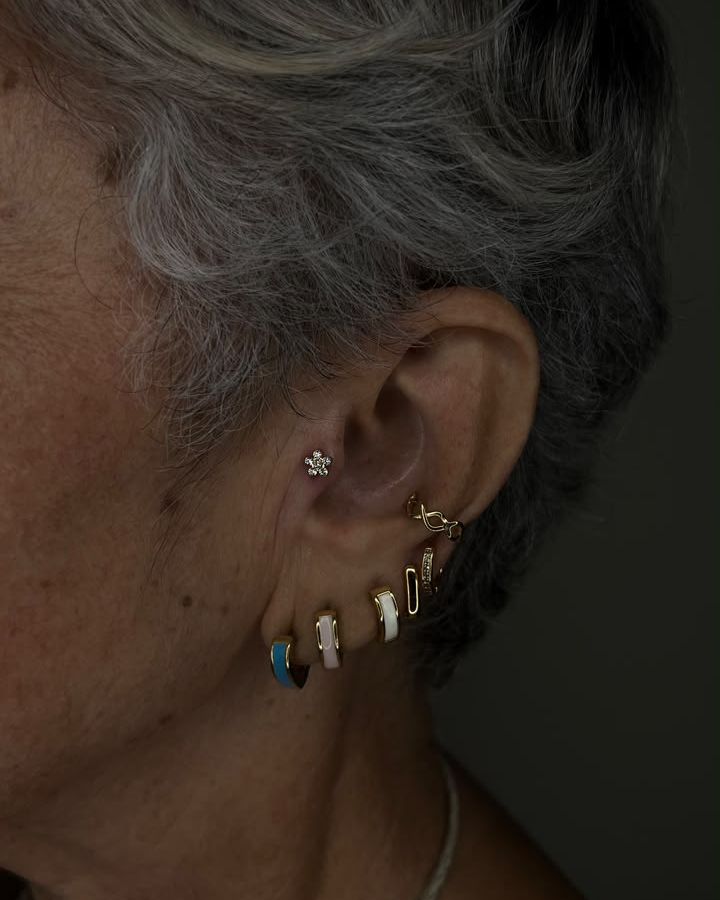 Orelha com perfurações e joias em titânio
